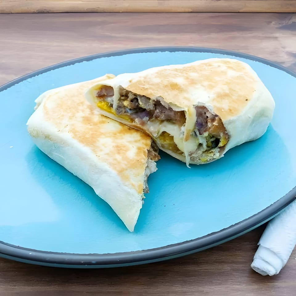 A grilled La Familia Cafe burrito, cut in half, revealing meat, cheese, and other fillings on a blue plate.