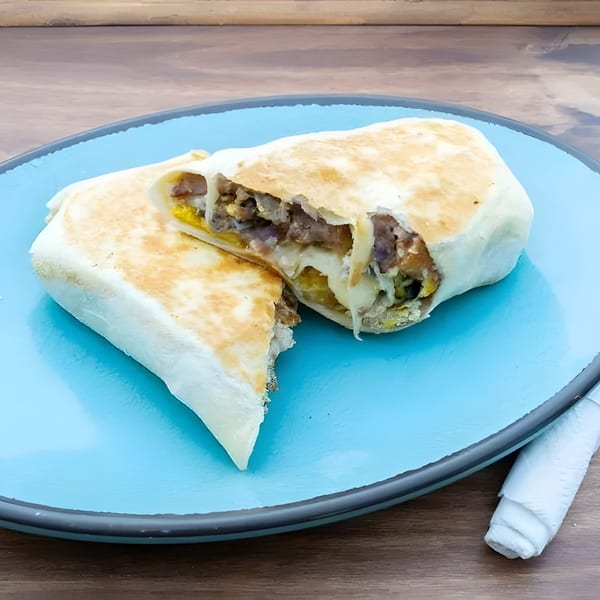 A large, cut La Familia Cafe burrito with meat, cheese, and beans on a blue plate.
