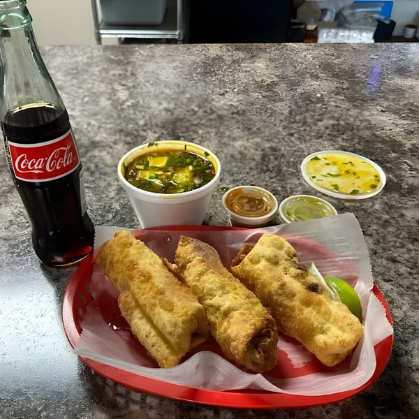 Three golden-fried flautas in a red basket with lime, a Coca-Cola, soup, and sauces.