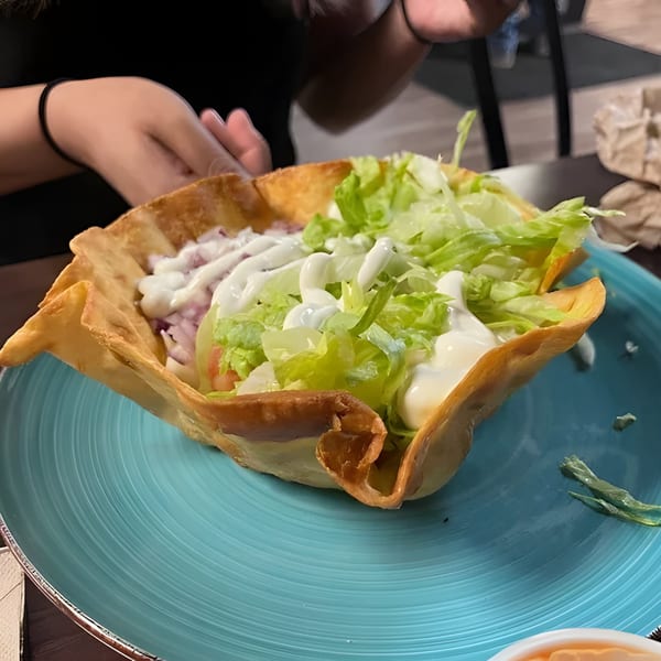 A La Familia Cafe taco salad in a crispy shell with lettuce, meat, and sour cream.